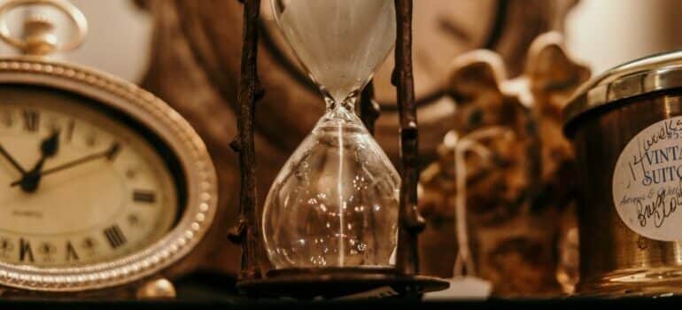 An antique hourglass surrounded by other antique items.