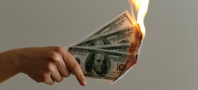 A person holding burning dollar bills.