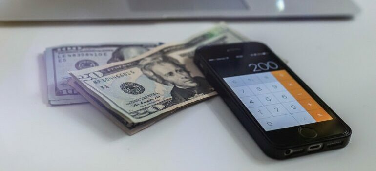 Dollar bills and a mobile phone for calculating moving quotes Austin.