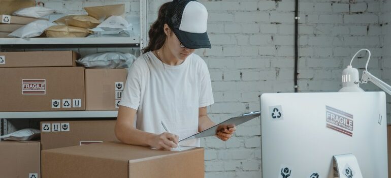 female with a hat working, moving boxes on the table and behind