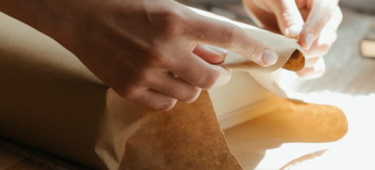 person using packing paper, packing an item for relocation