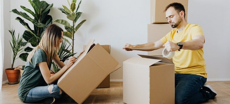 man and woman sitting on the floor and packing boxes