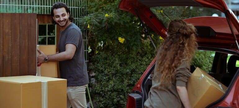 a man and a woman loading boxes into a car