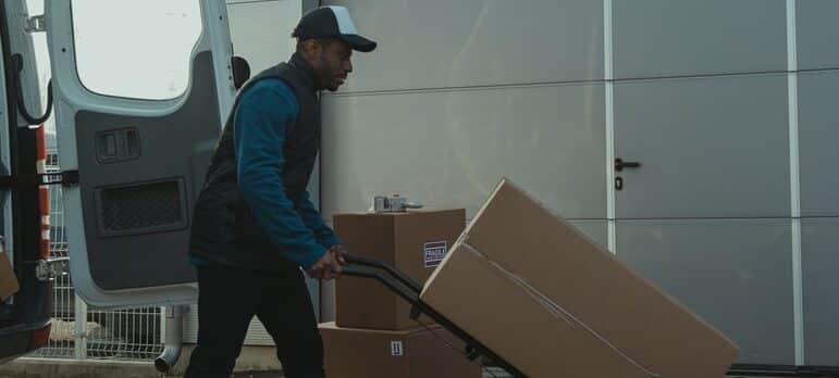 A guy using the dolly to move boxes