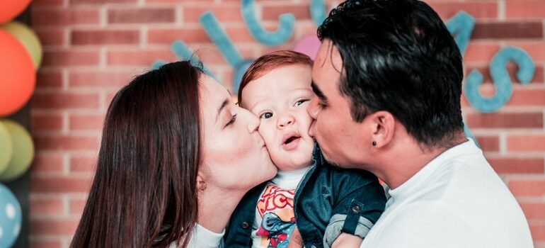 a couple kissing their toddler on the cheeks at the same time