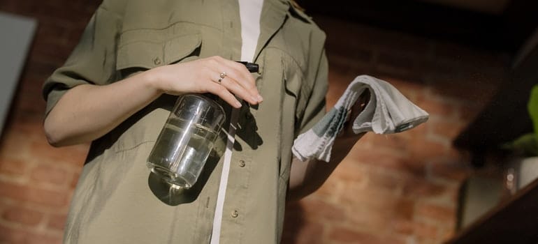 Woman holding a cloth and cleaning solution to pest-proof a storage unit