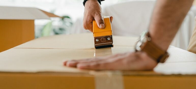 hand taping a box with duct tape 