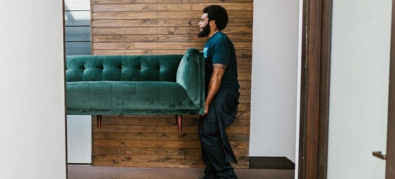 person carrying green sofa