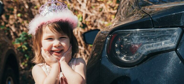child standing next to a car