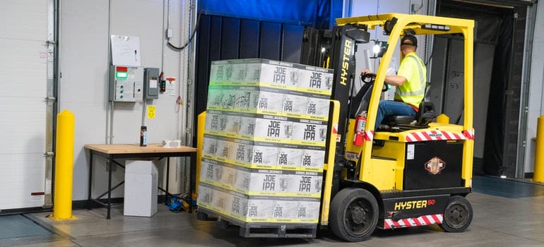 Man putting things in storage with forklift