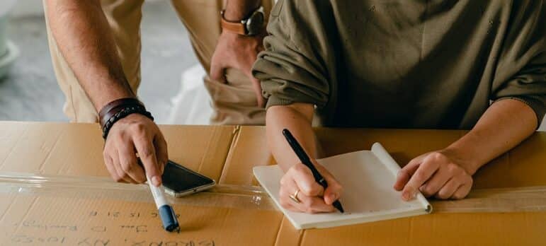 a couple writing down while packing and before moving from North Austin to South Austin