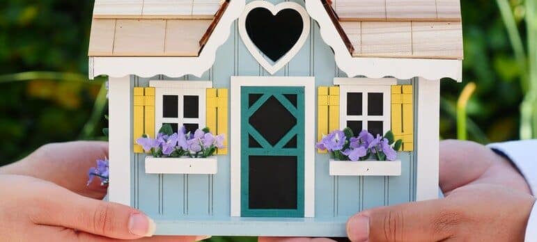 two people holding a miniature house