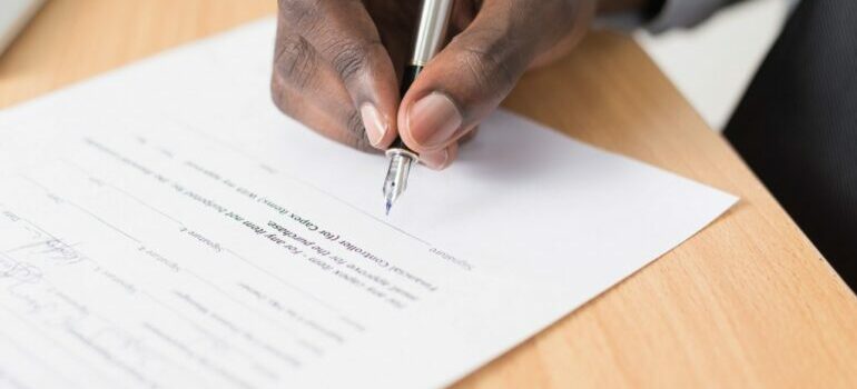 person signing a moving contract with packers for moving art collection
