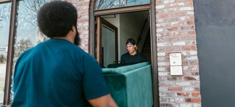 two movers carrying a couch outside of the house