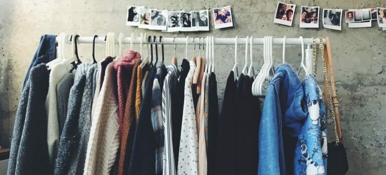 a rack of clothes with pictures above in a garage sale