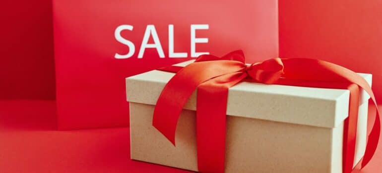 a cardboard box with a tie around it and a sign that says "sale" behind the box