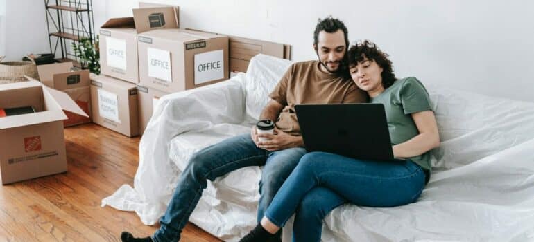 a couple sitting together on a sofa while taking a break from packing