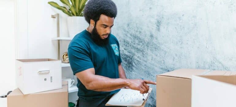 a moving crew personnel estimating the weight of cardboard boxes prior to moving them