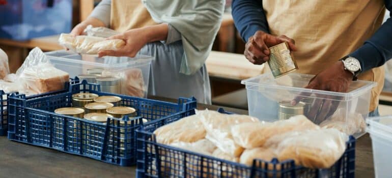 a couple packing food in different containers as a part of donation