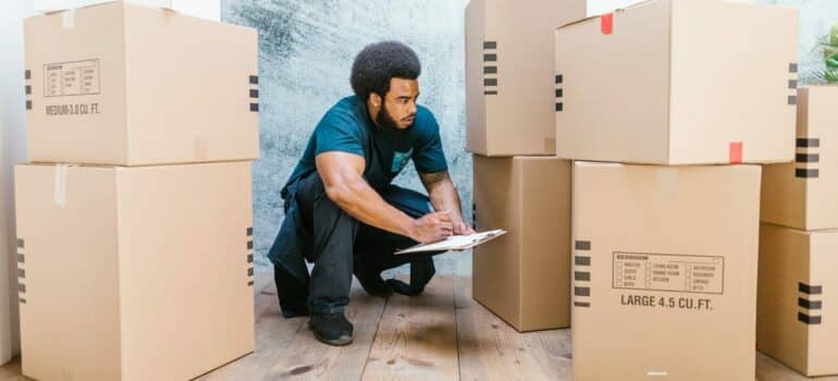 a mover crouching while making the list of all the items he has to move