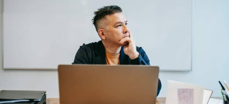a man sitting by his laptop thinking whether to choose flat-rate movers vs hourly movers