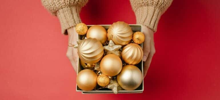 Person holding a box full with Christmas ornaments