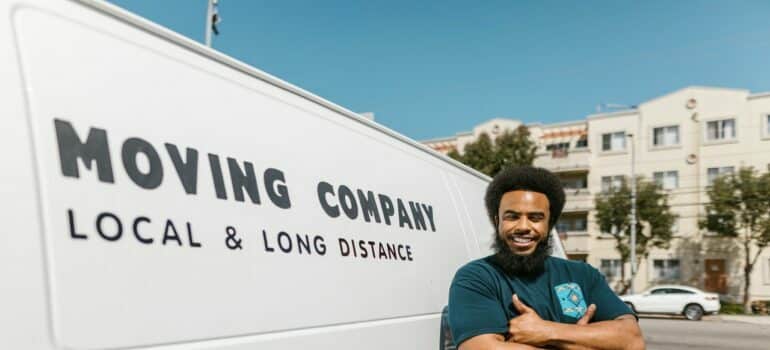 man in blue shirt standing beside moving van able to help moving your valuables