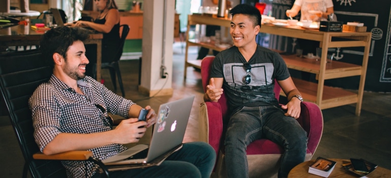 two friends sitting at a bar where one helps another evaluate moving companies in Texas