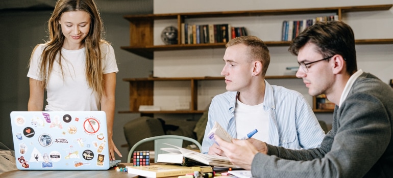 three young people discussing something in their living room