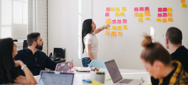 a team leader explaining the obligations of each team of employees using differently colored sticky notes