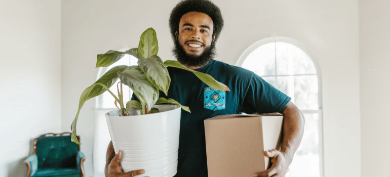 a man holding a box and a pot with plant