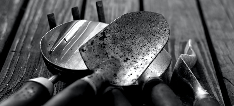 several gardening tools on a wooden table in black and white