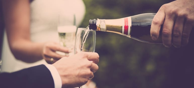 Person pouring champagne to the newly weds