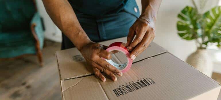 A mover closing a moving box with tape