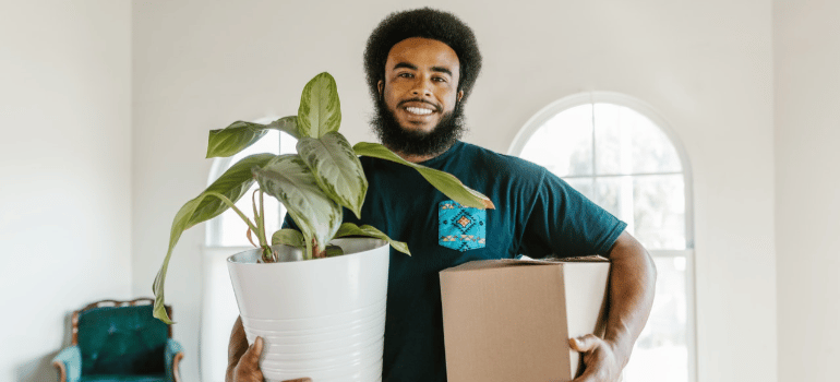 a man holding a box and a plant
