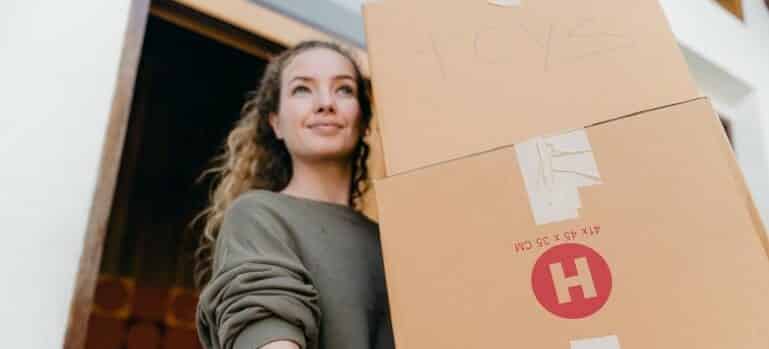 A woman holding boxes and thinking of things to know before looking for movers around you