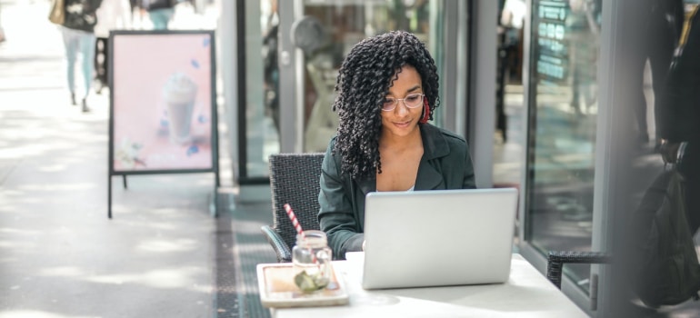 a woman sitting in public while researching something on her laptop