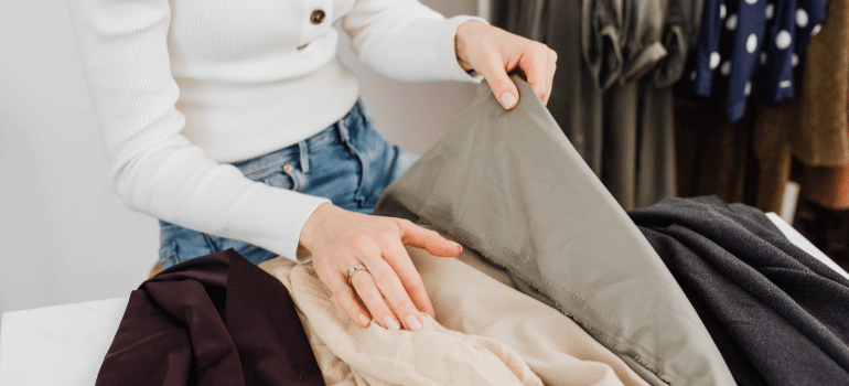a woman trying to organize clothes with cloth storage bins