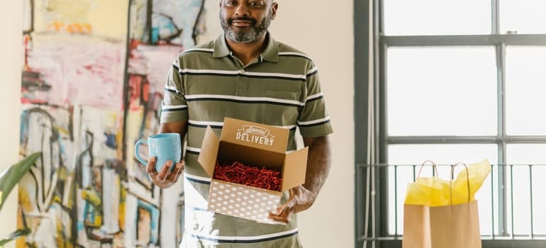 A man is holding a box and a cup to prepare for professional packers.