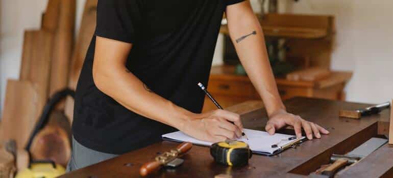 A person writing down measurments of their belongings