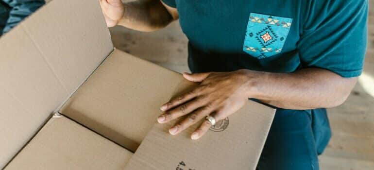 a person in a blue t-shirt holding a brown cardboard box