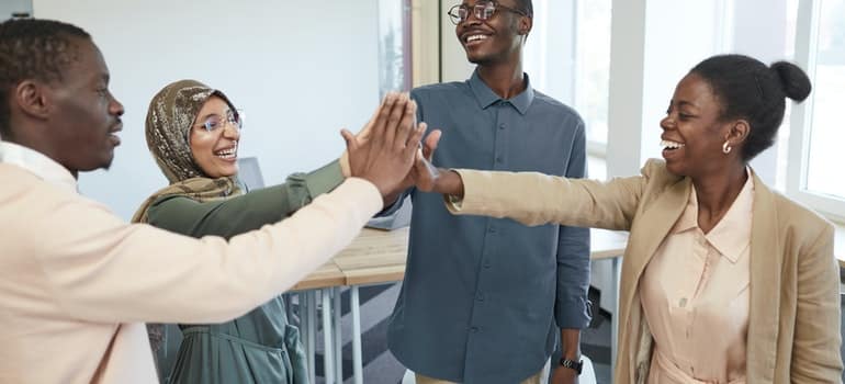 Four people smiling and touching hands