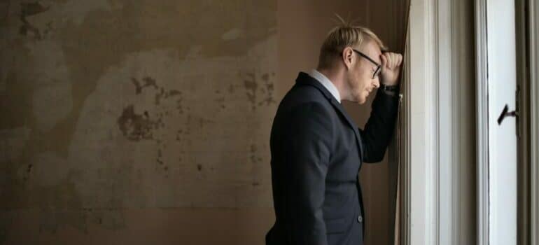 Man standing by the window thinking about renting in Westlake after an eviction