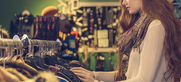 Woman Wearing White long-sleeved shirt with scarf standing near clothes