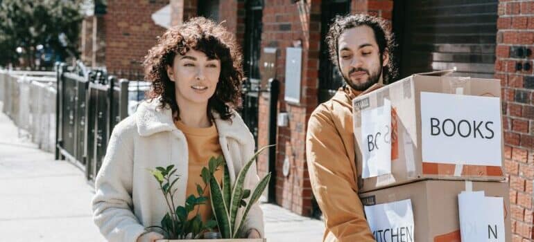 Couple carrying labeled moving boxes