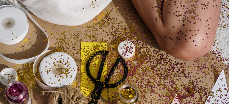 A woman sitting in a big mess she made while crafting